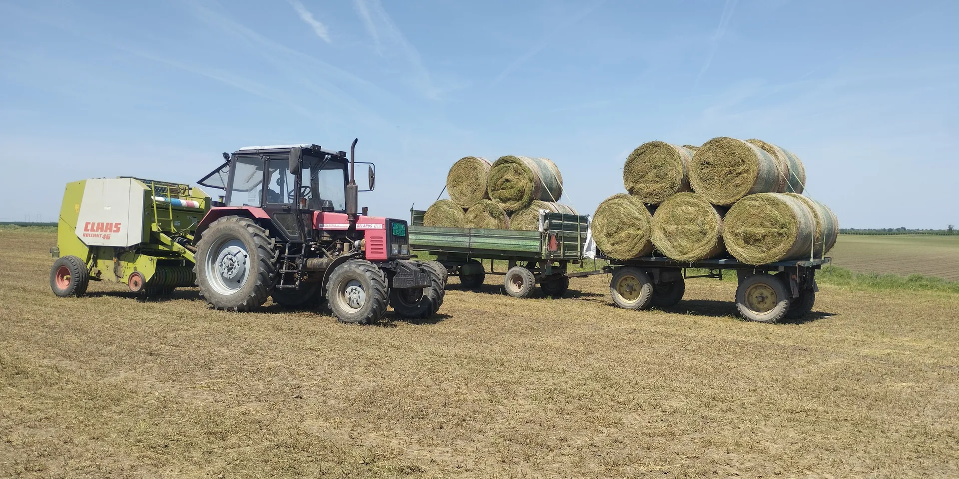 Traktor sa balirkom i rolo bale na njivi